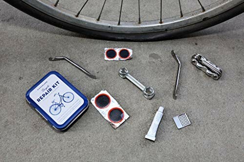 Bicycle tire repair kit with tools and patches on the ground.