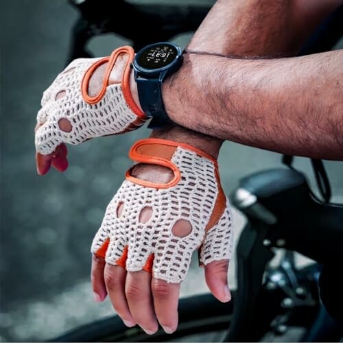 Person wearing cycling gloves and a smartwatch on a bike